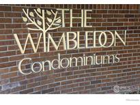 The Wimbledon Condominiums signage made of gold metal lettering on a red brick wall at 3000 Colorado Ave # 115, Boulder, CO 80303