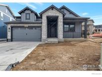 Gray two-story home featuring stone accents, a covered porch, and an attached two-car garage at 461 Muirfield Cir, Louisville, CO 80027