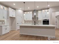 Modern kitchen features white cabinets, stainless steel appliances, and a large center island, perfect for cooking and entertaining at 461 Muirfield Cir, Louisville, CO 80027