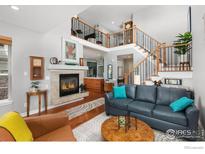 Inviting living room with a fireplace, staircase, hardwood floors, and comfortable furnishings at 8887 Tappy Toorie Cir, Highlands Ranch, CO 80129