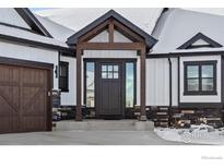Inviting front door with wood trim and sidelight windows, complemented by stone accents and a covered porch at 1291 Swan Peter Dr, Berthoud, CO 80513