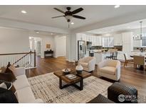 Bright, open-concept living space flows into the kitchen with hardwood floors and modern finishes at 14189 St Paul St, Thornton, CO 80602