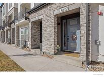 Charming townhome exterior showcasing a stone facade and inviting blue front door with a wreath and address number at 2272 Old Rail Way, Superior, CO 80027