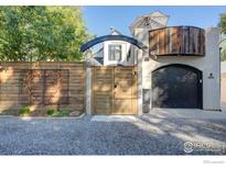 Unique stucco home with a wooden fence featuring a heart decor, arched entrance, and a balcony at 2434 Mapleton Ave, Boulder, CO 80304