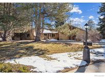 Inviting front yard with mature trees and some snow-covered grass at 320 Glenview Ct, Longmont, CO 80504