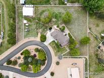 Expansive property featuring a home with circular driveway, mature trees, outbuildings, and fenced perimeter at 3784 Whitetail Ct, Mead, CO 80542