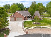 Charming brick home with three-car garage and a well-manicured lawn and white fencing at 3784 Whitetail Ct, Mead, CO 80542