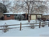 Charming brick home featuring an attached garage and mature tree in a snow-covered front yard at 614 Munson Ct, Berthoud, CO 80513