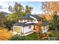 Two-story modern home with a black roof, three-car garage and lush landscaping on a sunny day at 1385 Kalmia Ave, Boulder, CO 80304