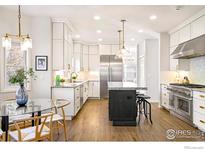 Modern kitchen featuring white cabinets, stainless steel appliances, and a contrasting dark island with granite countertops at 1385 Kalmia Ave, Boulder, CO 80304