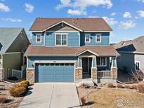 Charming two-story blue home featuring a covered front porch, two car garage and manicured landscaping at 1417 Bluemoon Dr, Longmont, CO 80504