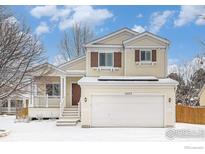 Charming two-story home with a two-car garage and covered front porch during the winter at 1577 Bain Dr, Erie, CO 80516