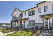 Modern townhome exterior featuring white and gray siding, black accents, and landscaped front yard with a wrought iron fence at 2723 Bear Springs, Longmont, CO 80503