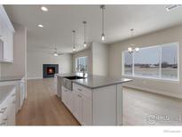 Bright, open kitchen features a large island, modern pendant lighting, and sleek white cabinetry at 5755 Pintail Way, Frederick, CO 80504