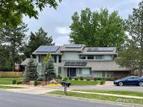 Two story home with stone accents, manicured lawn, mature trees, and solar panels at 7240 Clubhouse Rd, Boulder, CO 80301