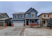 Charming two-story blue home with a two-car garage and red brick accents at 739 Graham Cir, Erie, CO 80516