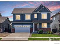 Charming two-story home showcasing a brick-accented facade, a well-manicured lawn, and an attached two-car garage at 739 Graham Cir, Erie, CO 80516