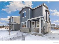 Charming two-story home featuring a welcoming front porch with stone accents and a modern gray exterior at 1059 Spartan Ave, Berthoud, CO 80513