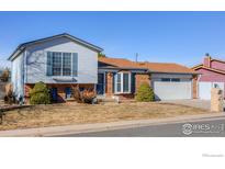 Charming two-story home with brick and light blue siding, complemented by mature landscaping and a two-car garage at 1135 Fern St, Broomfield, CO 80020