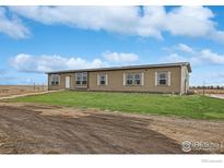 Tan single-story home featuring shuttered windows and landscaped front yard at 1363 S Edgar Ct, Strasburg, CO 80136