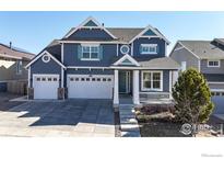 Charming blue two-story home with a three-car garage and covered front porch at 18690 W 84Th Dr, Arvada, CO 80007