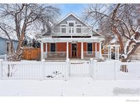 Charming two-story red brick home featuring a second story balcony and inviting front porch, surrounded by a white picket fence at 2137 Mapleton Ave, Boulder, CO 80304