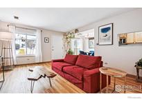 Bright living room featuring hardwood floors, large windows, and a comfortable red sofa at 2557 S Dover St # 30, Lakewood, CO 80227