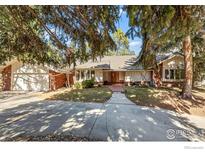 Inviting brick home with mature trees, attached garage, and a concrete driveway and walkway at 4862 Silver Sage Ct, Boulder, CO 80301