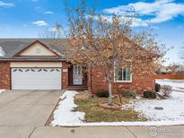 Charming brick home featuring an attached garage and well-maintained landscaping with budding tree at 1737 Grove Ct, Longmont, CO 80501