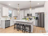 Modern kitchen featuring white cabinets, stainless steel appliances, and center island with seating at 182 Sassafras St, Erie, CO 80516