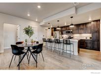 Bright, modern kitchen featuring wood floors, dark cabinets, a white countertop island, and barstool seating at 265 High Point Dr # 101, Longmont, CO 80504