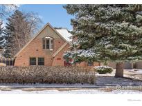 Charming brick home with snowy trees, featuring a unique red front door and bay window at 3584 Kirkwood Pl, Boulder, CO 80304