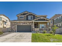 Charming two-story home featuring stone accents, a covered front porch, and a well-maintained front lawn at 458 Highlands Cir, Erie, CO 80516