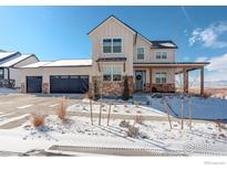 Charming two-story home features a three-car garage, stone accents and covered porch in a winter landscape at 711 William Way, Berthoud, CO 80513