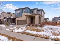 Two-story home featuring a mix of stone and blue siding, attached garage, and covered front entry at 956 Equinox Dr, Erie, CO 80516