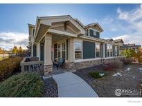 Charming home exterior with a covered porch, stone accents, and lush landscaping at 509 Brennan Cir, Erie, CO 80516