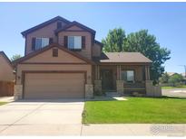 Charming two-story home with a well-manicured lawn and inviting front porch at 548 Mathews Cir, Erie, CO 80516