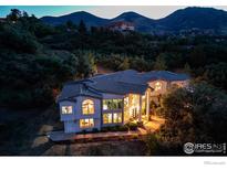 Stunning home featuring expansive windows and beautiful mountain views at twilight at 5799 Crestbrook Cir, Morrison, CO 80465