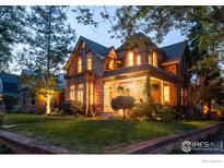 Charming stone home with a well-manicured lawn and inviting porch, illuminated by warm lighting at dusk at 643 Mapleton Ave, Boulder, CO 80304