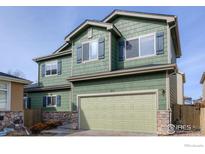 Charming two-story home with green siding, stone accents, and a two-car garage at 10117 Wyandott N Cir, Thornton, CO 80260