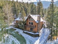 Inviting mountain home with stone chimney, balconies, and views of the surrounding forest at 1170 Elk Valley Dr, Evergreen, CO 80439