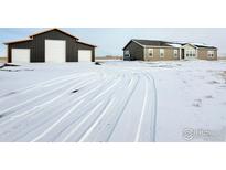 Charming home featuring a spacious garage, set amidst a serene snowy landscape at 17910 County Road 38, Platteville, CO 80651