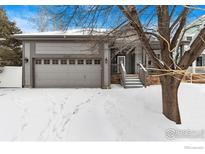 Charming gray home featuring an attached garage and snowy front yard at 2112 Springs Pl, Longmont, CO 80504