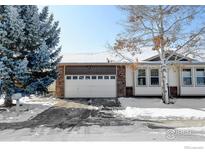 Charming home featuring a two-car garage with stone accents and a well-maintained front yard in a wintery landscape at 3025 Depo Dr, Longmont, CO 80503