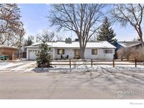 Charming brick home featuring an attached garage and cozy front porch seating, all nestled behind a rustic wooden fence at 390 W 3Rd Ave Dr, Broomfield, CO 80020