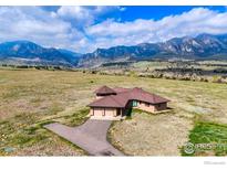 Stunning aerial view of a home with an attached garage, brown roof, and a scenic mountain backdrop under a partly cloudy blue sky at 4702 Eldorado Springs Dr, Boulder, CO 80303