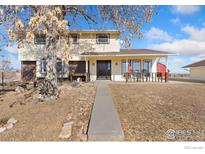 Charming two-story home with a covered porch, beautiful walkway, and large tree in the front yard at 9089 Vermillion Rd, Longmont, CO 80503