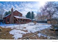 Spacious backyard featuring a covered patio, mature trees, and a partially snow-covered lawn at 106 Granada Ct, Longmont, CO 80504