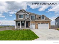 Two-story home showcasing stone accents, a two-car garage, well-manicured lawn, and mountain views at 1166 Ridgefield Dr, Berthoud, CO 80513