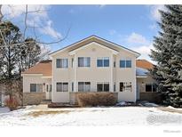 Two-story condo featuring neutral siding, complemented by well-maintained landscaping and a snow covered yard at 2143 Meadow Ct, Longmont, CO 80501